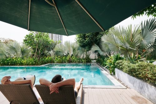 para relaksująca się na leżakach nad basenem hotelowym z widokiem na roślinność