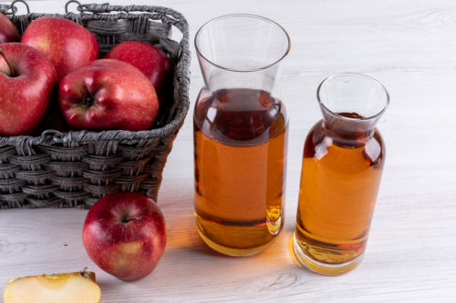 koszyk jabłek, obok karafki z sokiem jabłkowym
