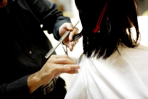 fryzjer podcinający włosy kobiecie