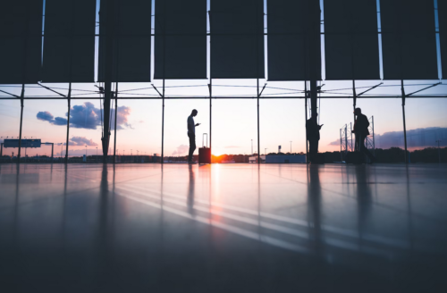 podróżujący mężczyzna samotnie stojący w oddali na lotnisku o zachodzie słońca