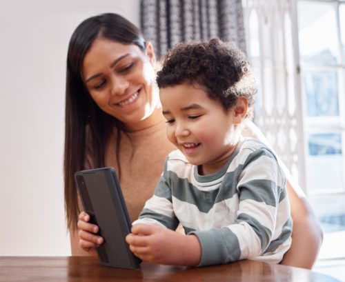 Ujęcie młodej matki i syna korzystających razem z telefonu w domu